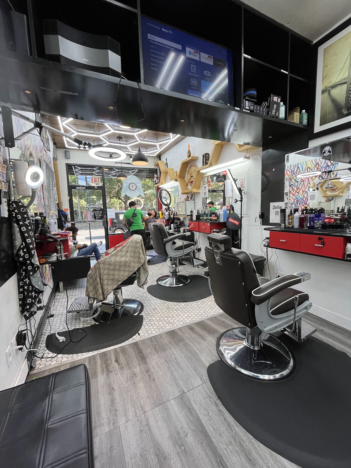Inside Lower East Side Barbers: two black barber chairs on hex-tile floor, mirrors, hexagon LED lights overhead