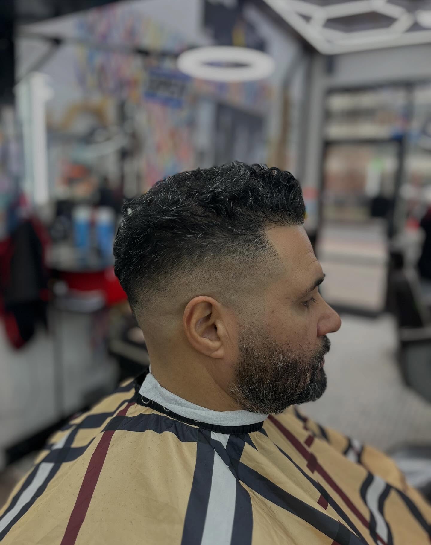Side profile of an older client with salt-and-pepper top, close fade and beard work